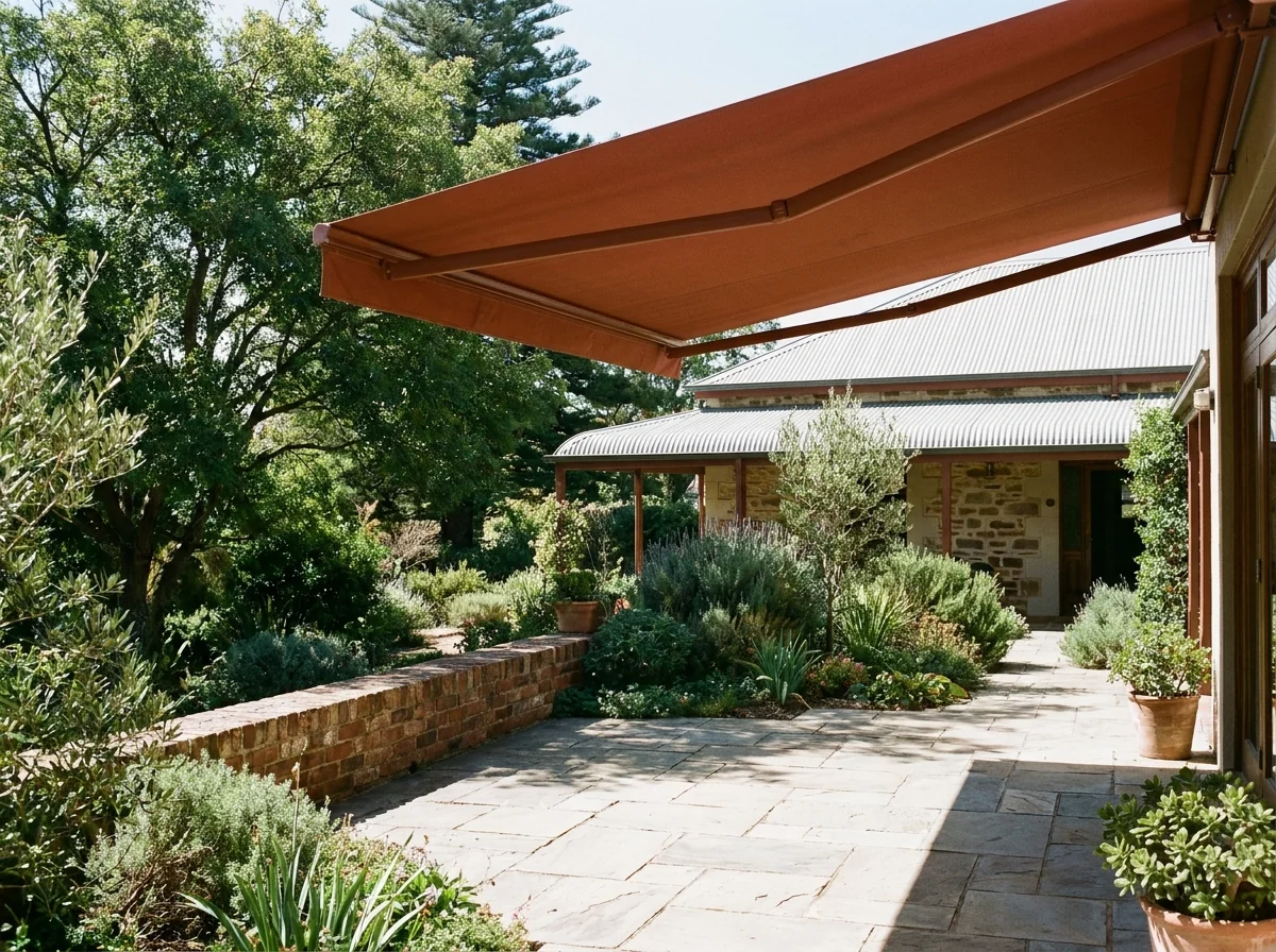 Parktown North stone patio with a terracotta folding-arm awning extended overhead beside established garden beds